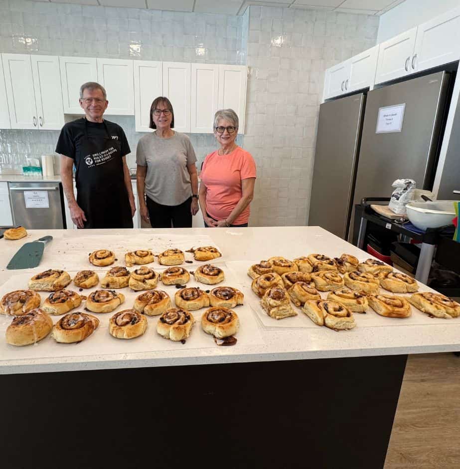 Three people with freshly baked cinnamon buns